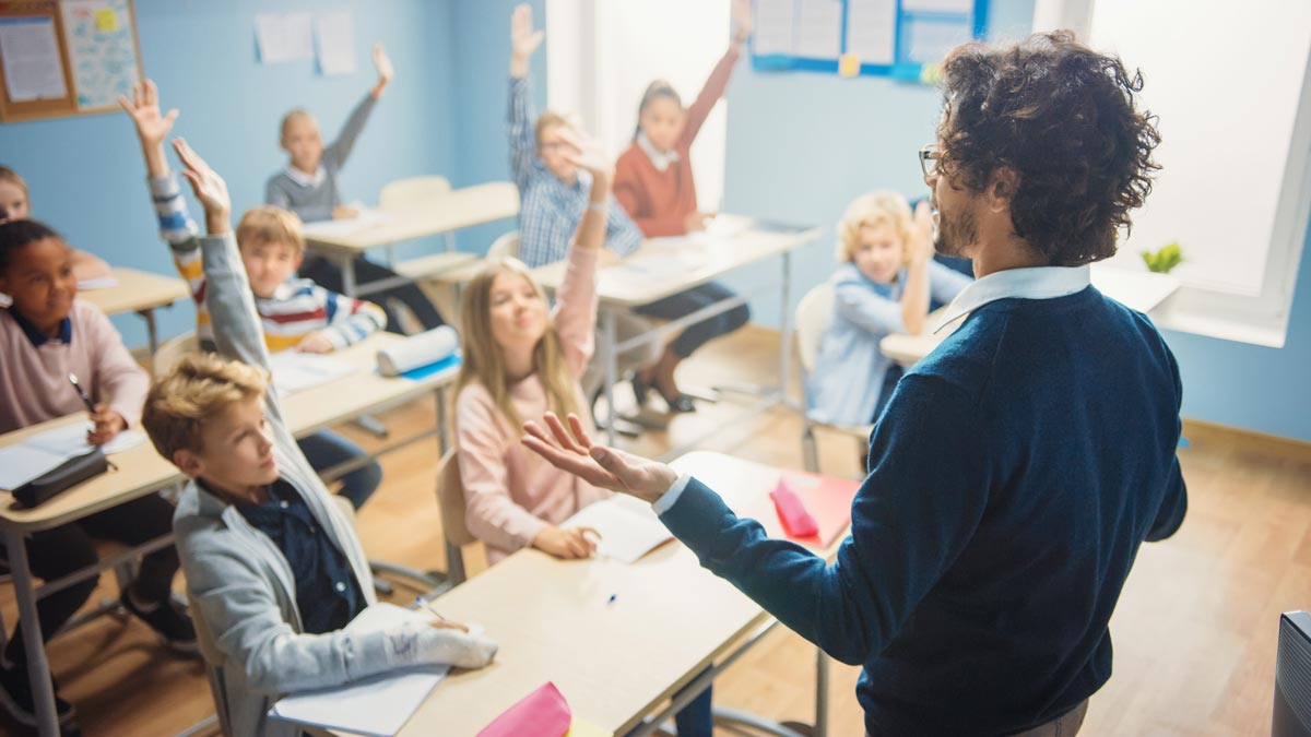 Students with hands raised in classroom